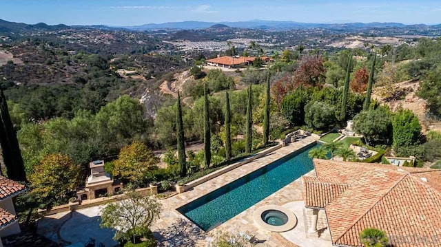 view of pool featuring a patio, an in ground hot tub, and a mountain view