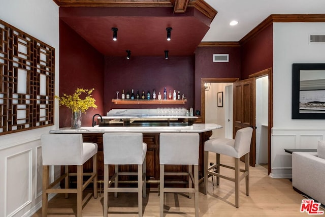 bar featuring crown molding and light hardwood / wood-style flooring