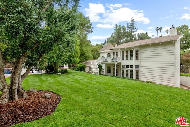 back of property featuring a patio area, a lawn, and a wooden deck