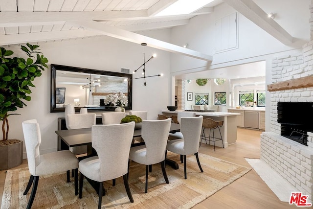 dining space with wooden ceiling, light wood-type flooring, lofted ceiling with beams, a notable chandelier, and a brick fireplace