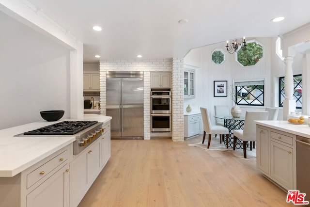 kitchen with an inviting chandelier, light wood-type flooring, a center island, and appliances with stainless steel finishes