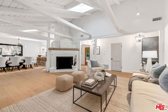 living room featuring light wood-type flooring, a brick fireplace, high vaulted ceiling, wood ceiling, and beam ceiling