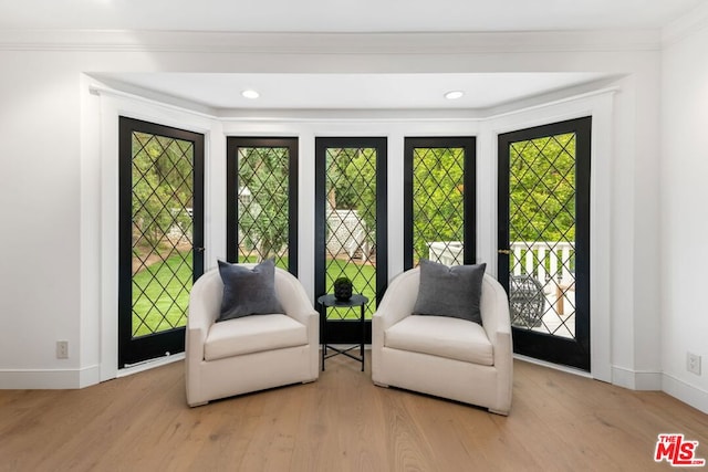 living area featuring light wood-type flooring and crown molding