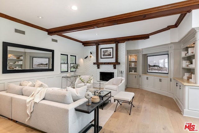 living room with beam ceiling, light hardwood / wood-style flooring, crown molding, and a fireplace