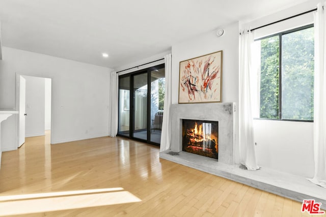 unfurnished living room with light wood-type flooring, plenty of natural light, and a fireplace