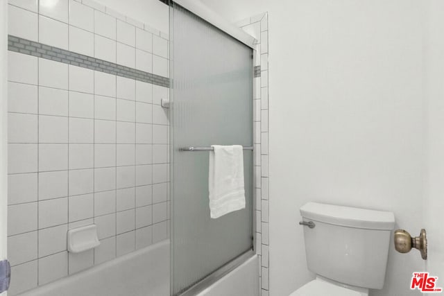 bathroom featuring toilet and combined bath / shower with glass door