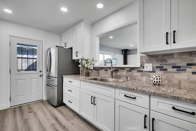 kitchen with sink, white cabinetry, light stone countertops, and tasteful backsplash