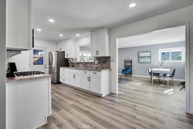 kitchen featuring white cabinets, gas cooktop, light hardwood / wood-style floors, and stainless steel fridge with ice dispenser