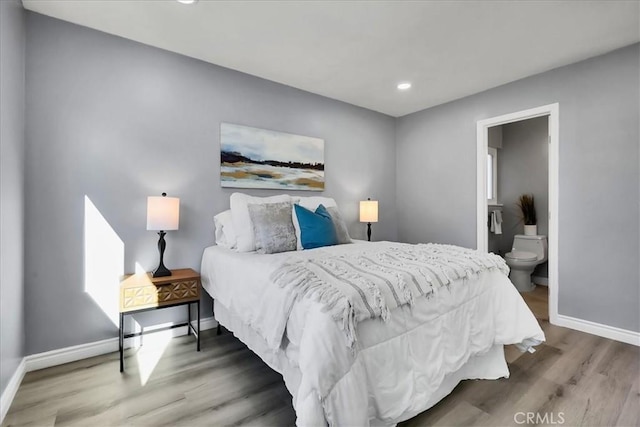 bedroom with ensuite bath and hardwood / wood-style floors