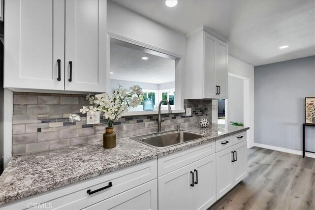 kitchen with light stone countertops, white cabinetry, tasteful backsplash, and sink