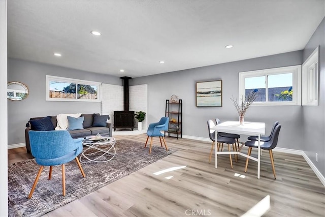 living room featuring light wood-type flooring, a wood stove, and plenty of natural light