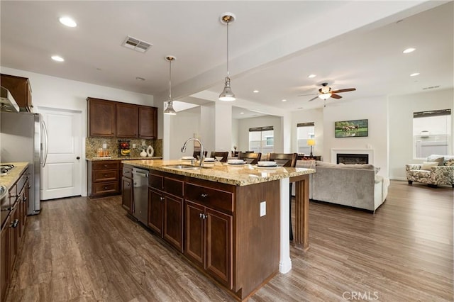 kitchen featuring hanging light fixtures, an island with sink, stainless steel appliances, a kitchen breakfast bar, and sink