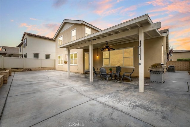 back house at dusk with ceiling fan and a patio