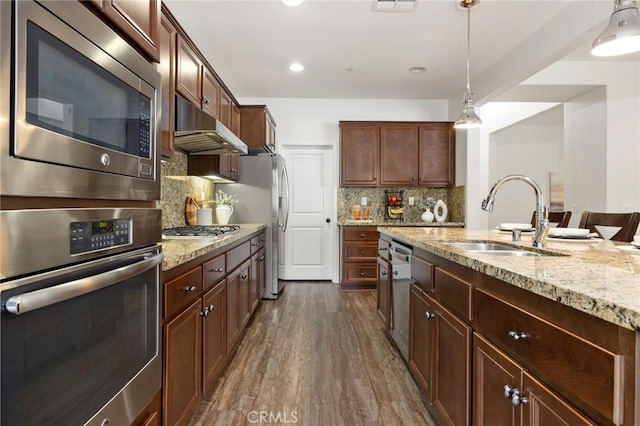 kitchen with stainless steel appliances, sink, backsplash, hanging light fixtures, and dark wood-type flooring