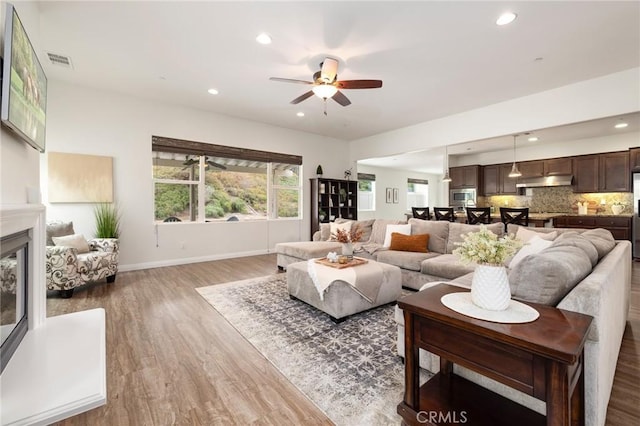 living room featuring wood-type flooring, ceiling fan, and a wealth of natural light