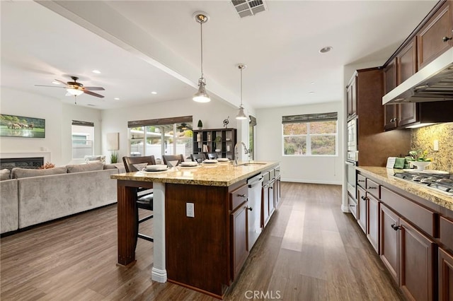 kitchen with a kitchen breakfast bar, a center island with sink, stainless steel appliances, hanging light fixtures, and sink