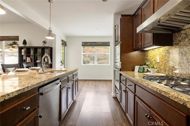 kitchen with decorative light fixtures, exhaust hood, tasteful backsplash, appliances with stainless steel finishes, and sink