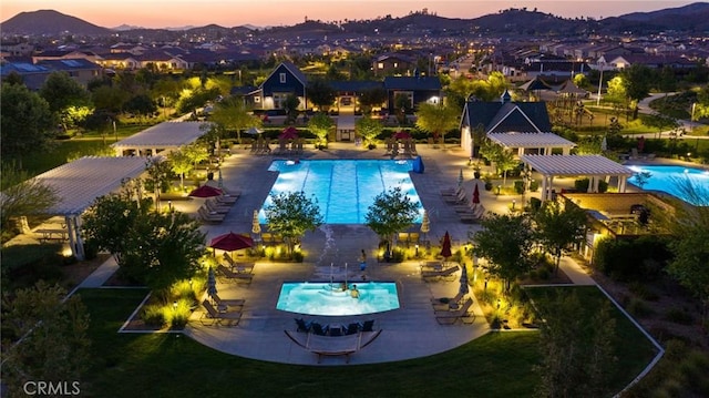 pool at dusk featuring a patio area, a pergola, and a mountain view