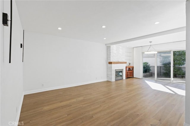 unfurnished living room featuring a stone fireplace and hardwood / wood-style flooring