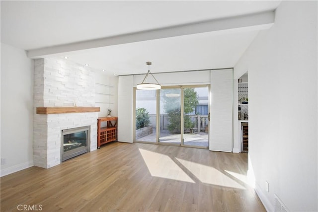 unfurnished living room featuring a fireplace, built in features, light hardwood / wood-style flooring, beverage cooler, and lofted ceiling with beams