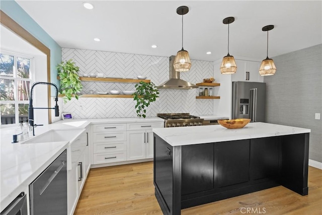 kitchen with stainless steel appliances, a kitchen island, white cabinets, and wall chimney range hood