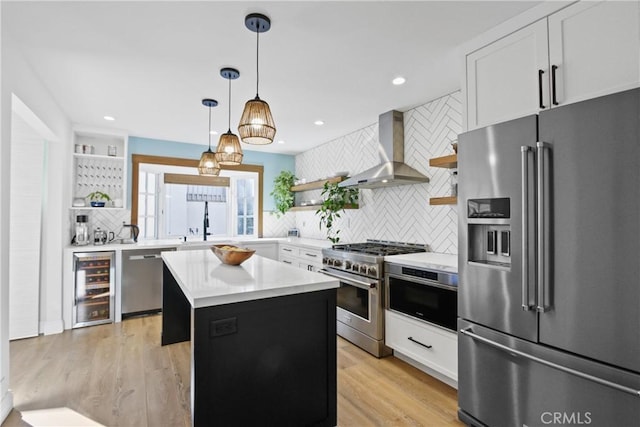 kitchen featuring white cabinets, a center island, high end appliances, beverage cooler, and wall chimney range hood