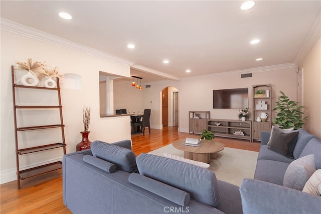 living room with light wood finished floors, arched walkways, and crown molding