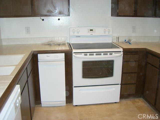 kitchen with sink, white appliances, and dark brown cabinetry