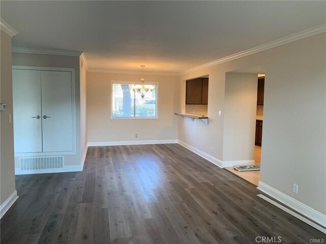 unfurnished living room featuring dark hardwood / wood-style flooring, an inviting chandelier, and crown molding