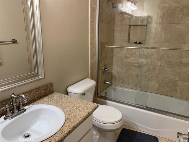 full bathroom with toilet, bath / shower combo with glass door, and vanity