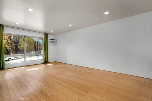 spare room featuring light wood-type flooring and a wall unit AC