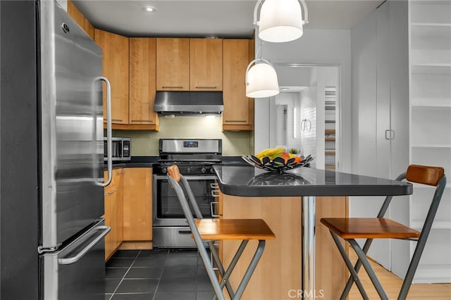 kitchen featuring stainless steel appliances, decorative light fixtures, a kitchen bar, and dark tile patterned flooring