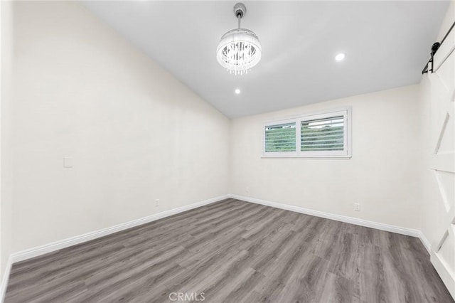 unfurnished room featuring an inviting chandelier and hardwood / wood-style flooring