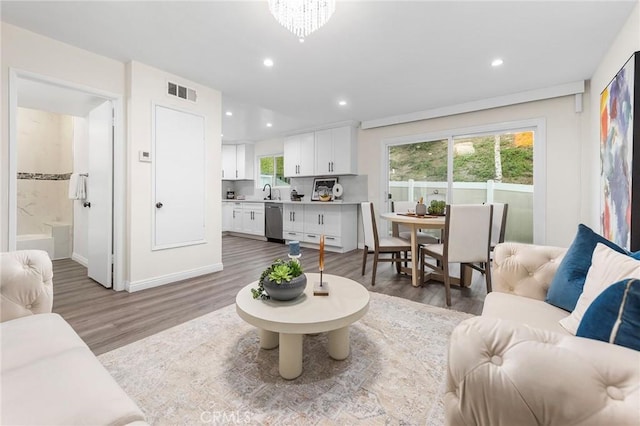 living room with sink, an inviting chandelier, and hardwood / wood-style flooring