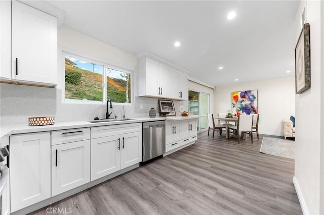 kitchen featuring plenty of natural light, stainless steel dishwasher, white cabinetry, and sink