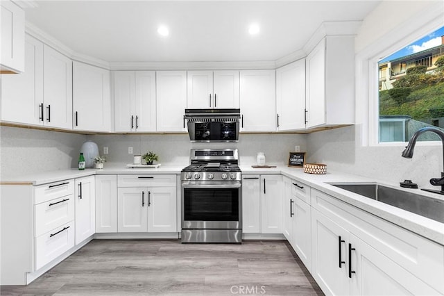 kitchen featuring stainless steel gas stove, white cabinetry, and sink