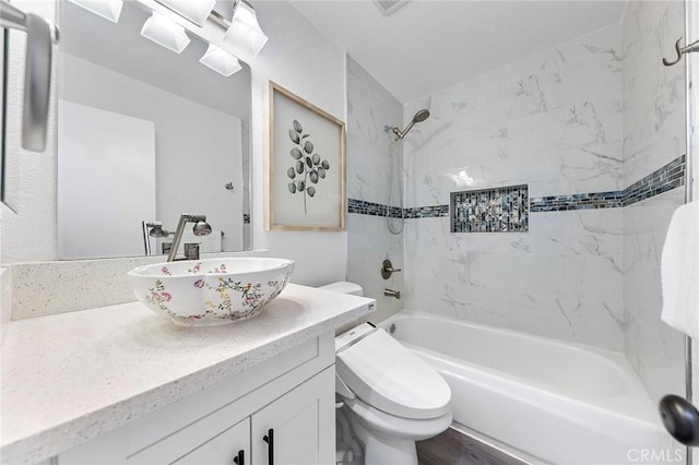 full bathroom with toilet, tiled shower / bath, hardwood / wood-style floors, and vanity