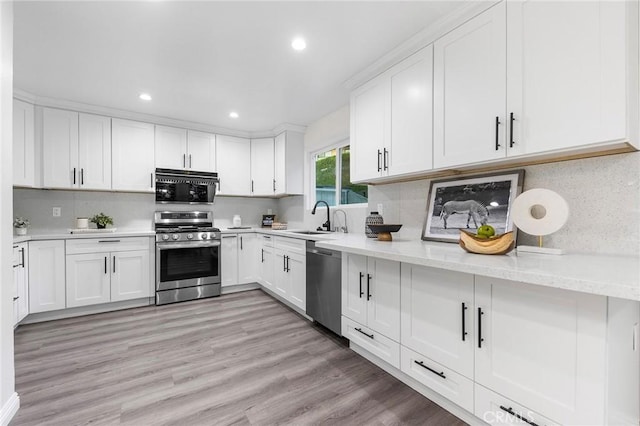 kitchen with sink, white cabinets, backsplash, and appliances with stainless steel finishes