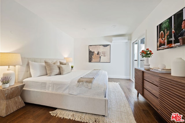 bedroom with dark hardwood / wood-style flooring and a wall mounted AC