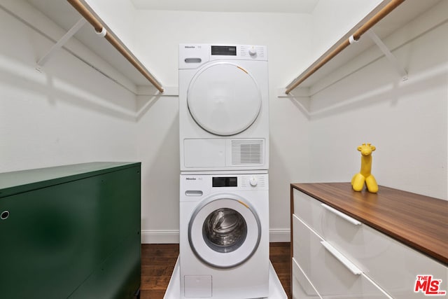 clothes washing area with stacked washer and dryer and dark hardwood / wood-style floors