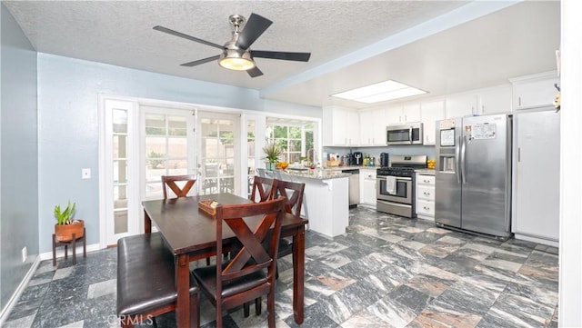 kitchen with appliances with stainless steel finishes, white cabinets, a textured ceiling, and light stone countertops