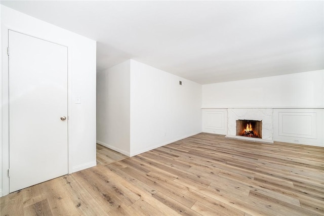 unfurnished living room with a fireplace and light hardwood / wood-style floors