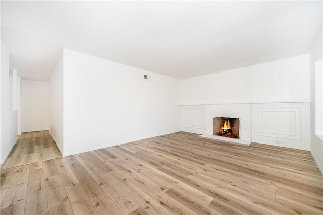 unfurnished living room featuring a premium fireplace and light wood-type flooring