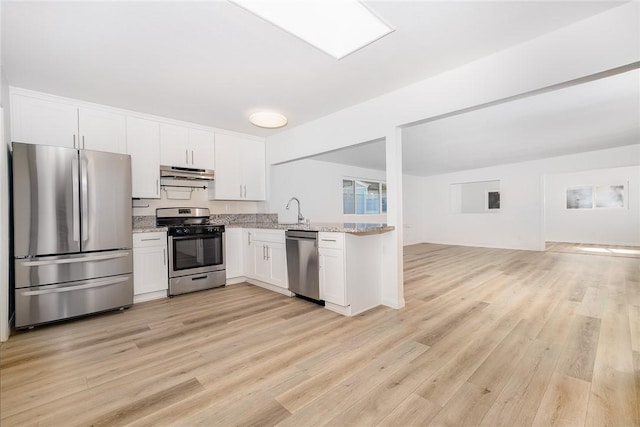 kitchen with stainless steel appliances, sink, white cabinetry, light stone counters, and light wood-type flooring