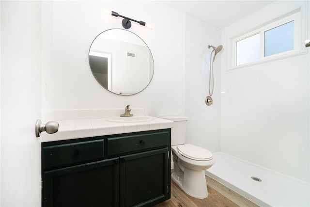 bathroom featuring toilet, a shower, vanity, and hardwood / wood-style floors