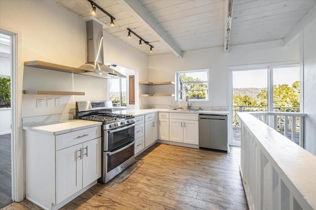 kitchen featuring white cabinetry, stainless steel appliances, wall chimney range hood, light hardwood / wood-style flooring, and sink