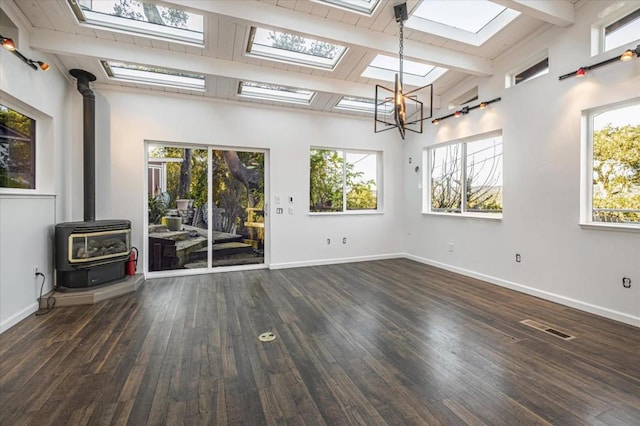 unfurnished living room featuring a notable chandelier, dark hardwood / wood-style flooring, lofted ceiling with beams, and a wood stove