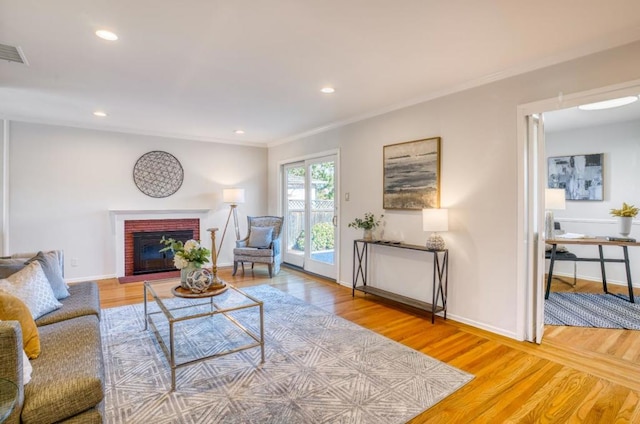 living room featuring crown molding, a fireplace, and hardwood / wood-style flooring