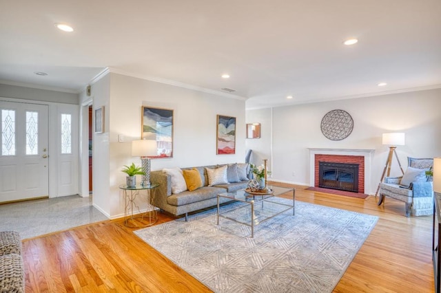 living room featuring a brick fireplace, hardwood / wood-style flooring, and ornamental molding