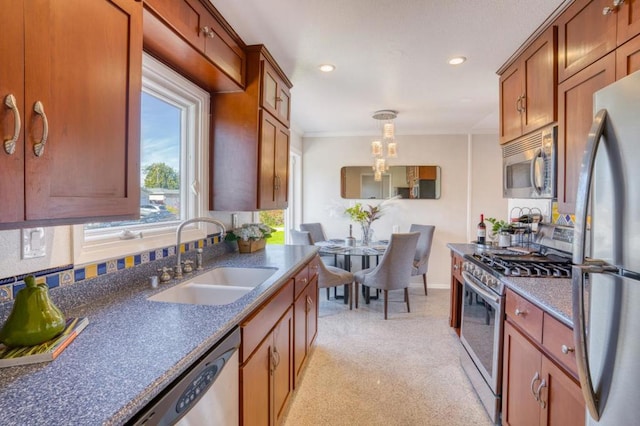 kitchen featuring stainless steel appliances, crown molding, hanging light fixtures, and sink